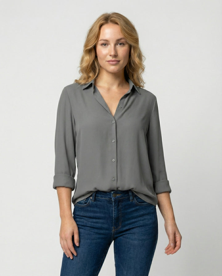 Female model wearing a long sleeve blouse with a classic collar on a plain background.