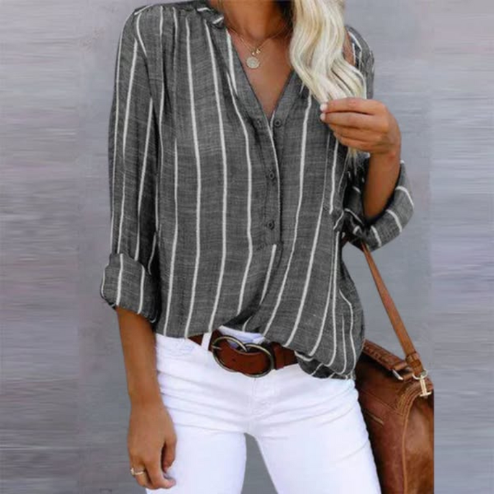 Woman model showcasing a relaxed striped long sleeve top on a plain background.