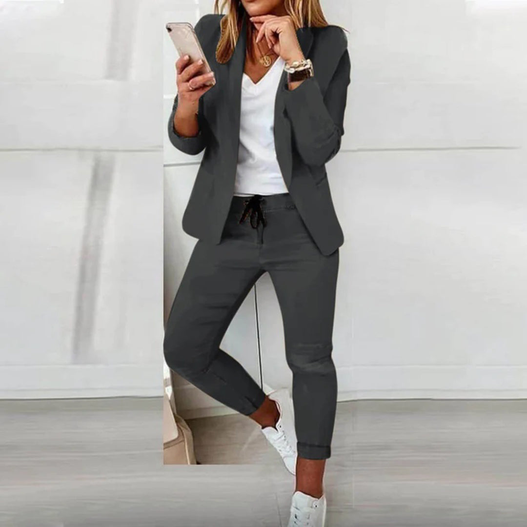 Woman wearing a polished two piece set with relaxed pants against a plain background.