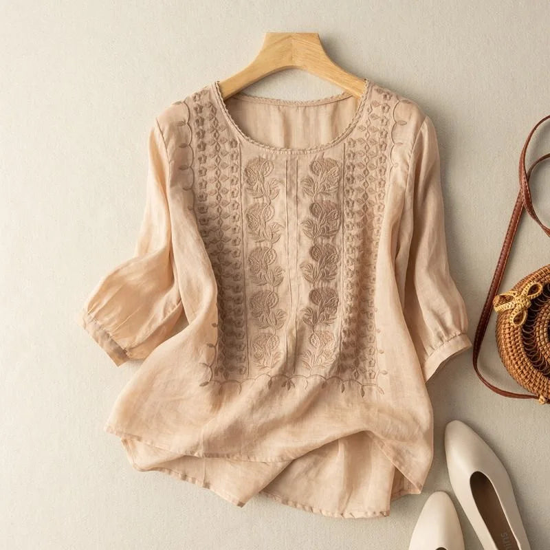 Lightweight embroidered blouse on hanger with plain background for everyday women’s wear.