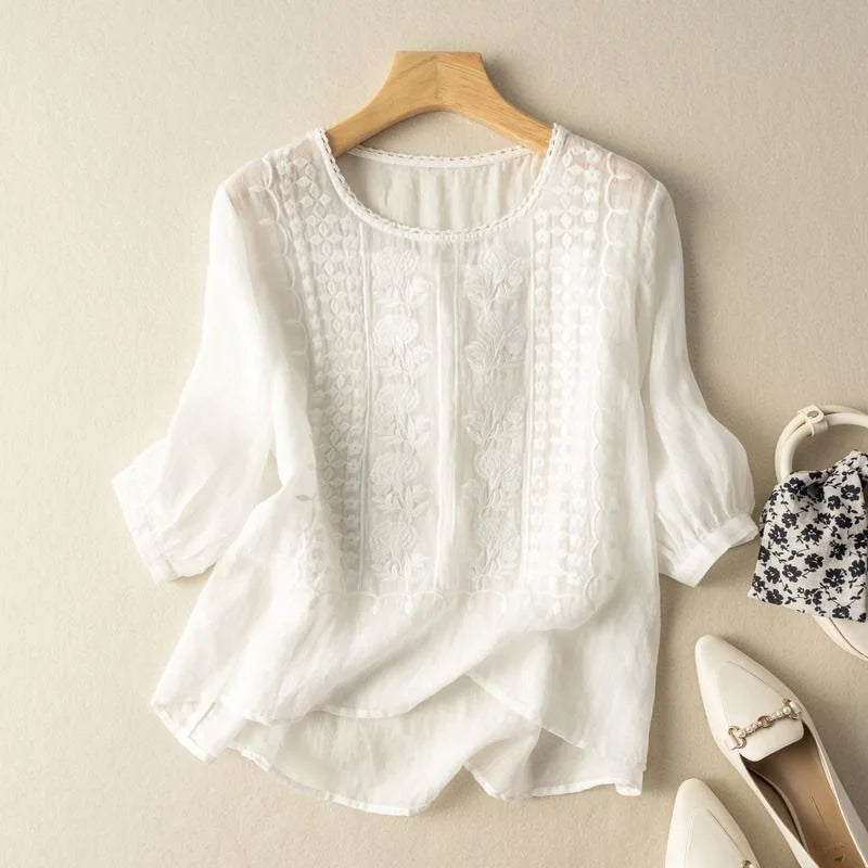Embroidered women’s top with cuffed sleeves styled on a hanger with plain background.