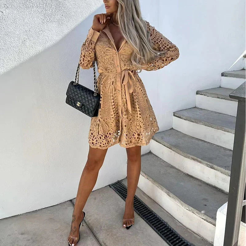  Woman showcasing a lace dress with elegant detailing and a flowing silhouette on a plain background.