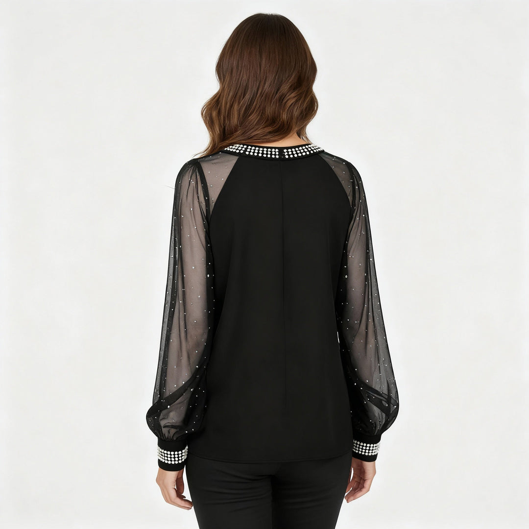 Woman showcasing a mesh top with sheer panels and sequin embellishments against a plain background.