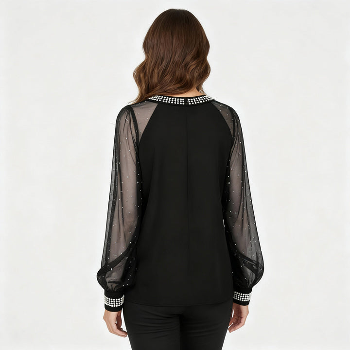Woman showcasing a mesh top with sheer panels and sequin embellishments against a plain background.