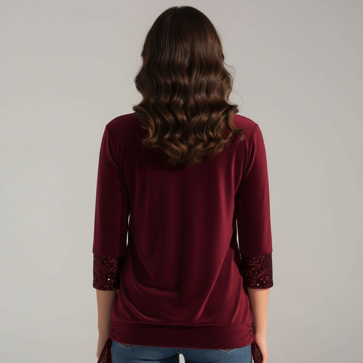 An elegant sequined blouse against a plain background.