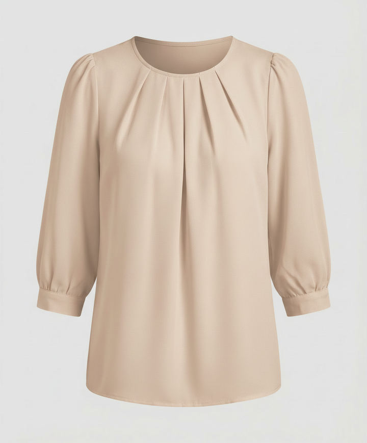 Woman in a satin blouse with elegant pleated accents against a plain backdrop.