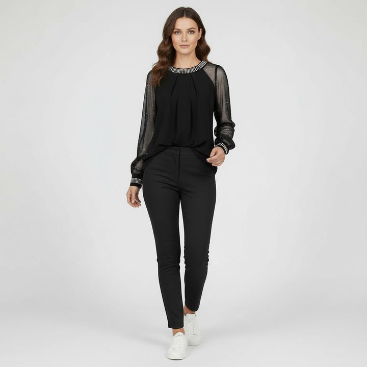 Woman in a sheer mesh top with sparkling accents and a round neckline on a plain background.