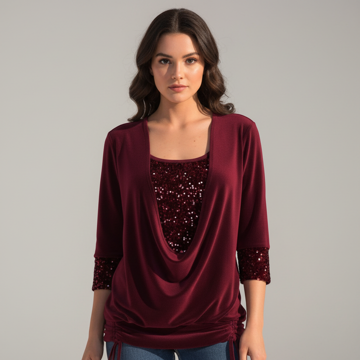 Woman wearing a shimmering long sleeve blouse on a plain background.
