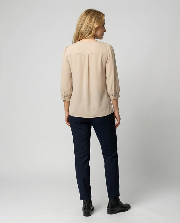 Female model in a stylish satin blouse with a timeless silhouette on a plain background.
