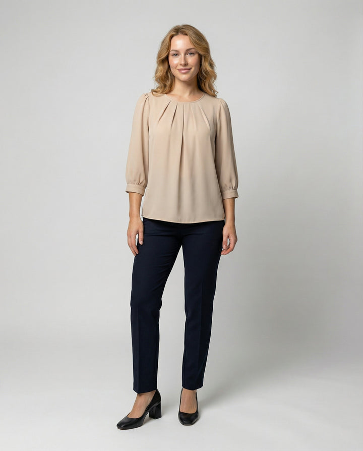 Woman showcasing a satin blouse with a soft sheen and refined pleated design.
