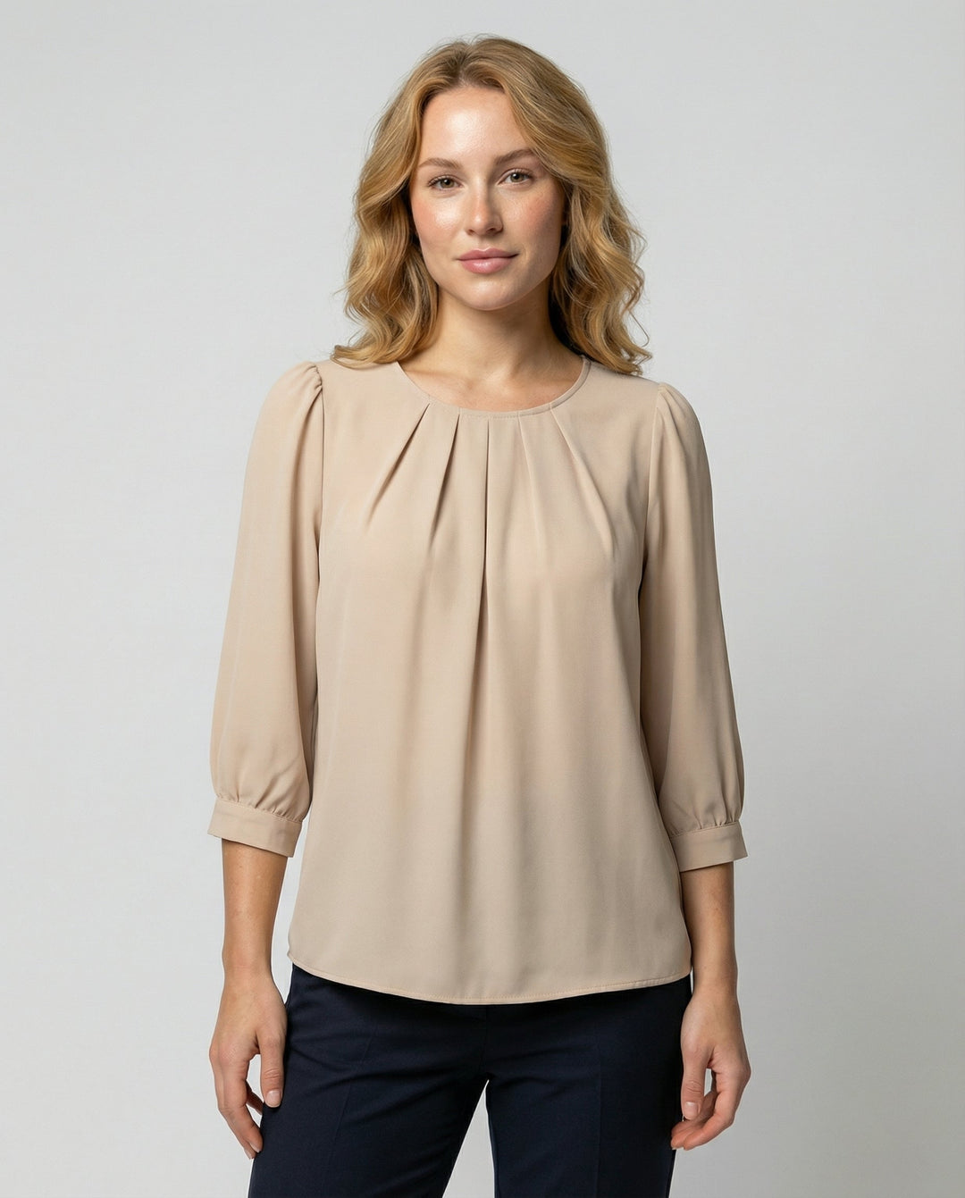 Female model wearing an elegant satin blouse with pleated detailing against a plain background.