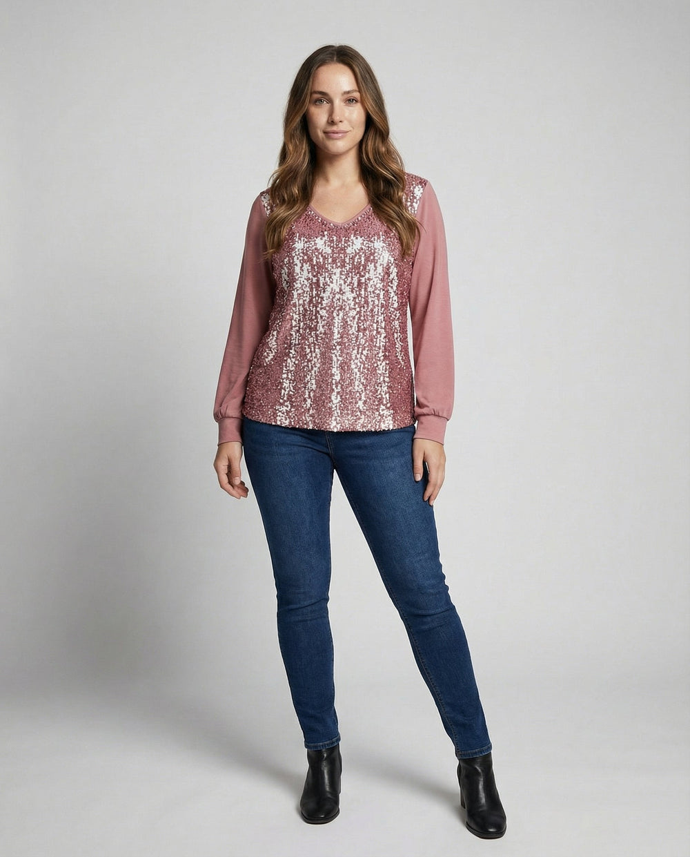 Woman in an elegant V-neck blouse with delicate shimmer accents on a plain background.
