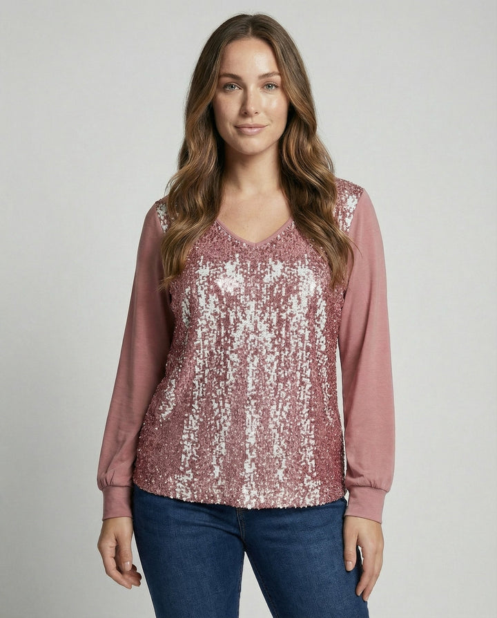 Female model wearing a glitter blouse with subtle sequin detailing against a plain background.

