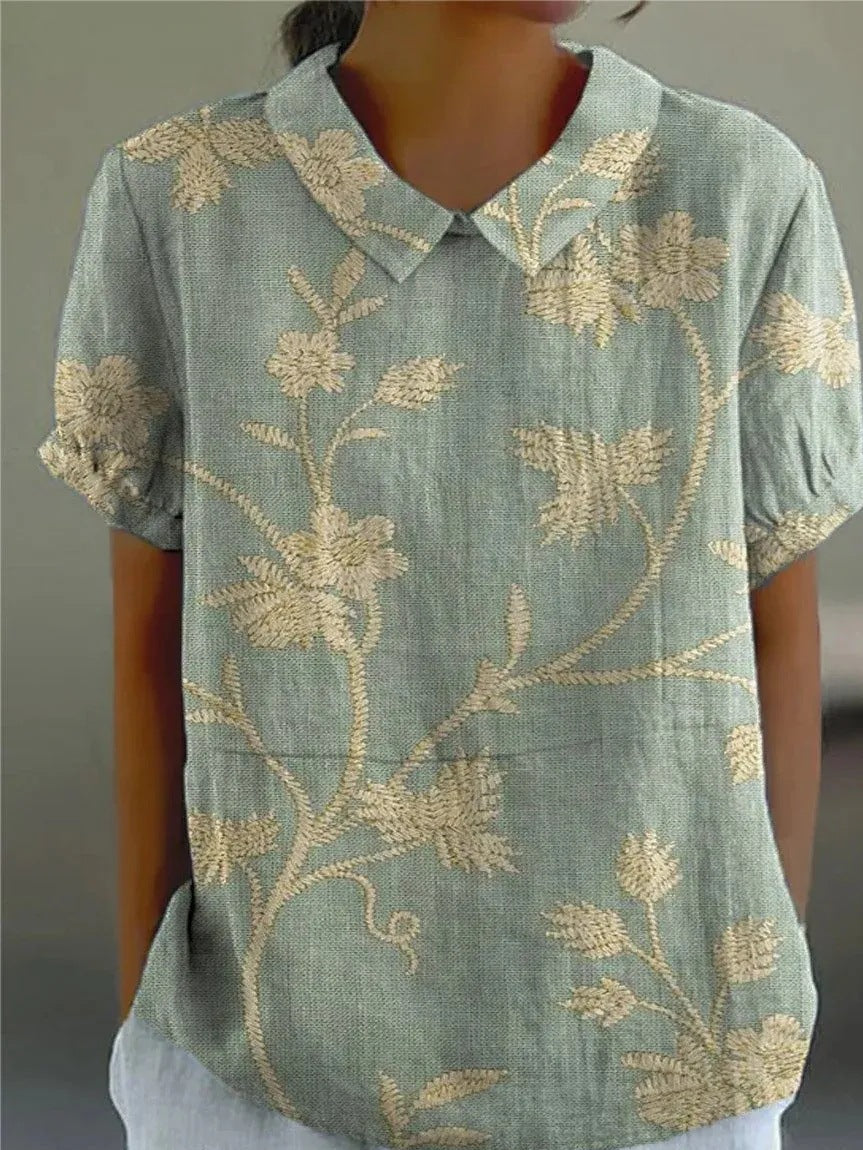 Female wearing a floral short sleeve blouse with a relaxed silhouette on a plain background.