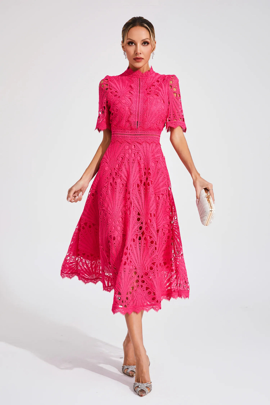 Stylish woman model posing in a lace A-line midi dress with cutout waist on a plain background.