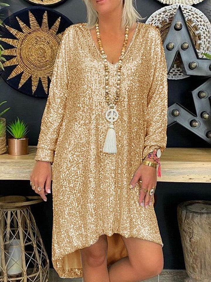  Woman showcasing a sparkling formal dress with long sleeves on a plain background.