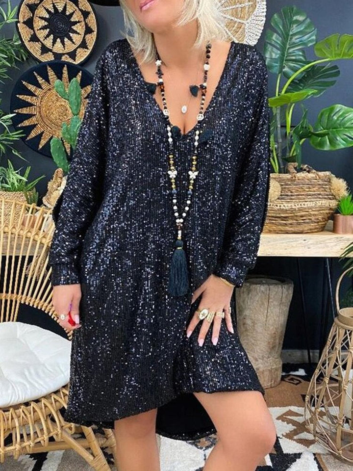 Female model wearing a shimmering long sleeve evening dress against a plain background.