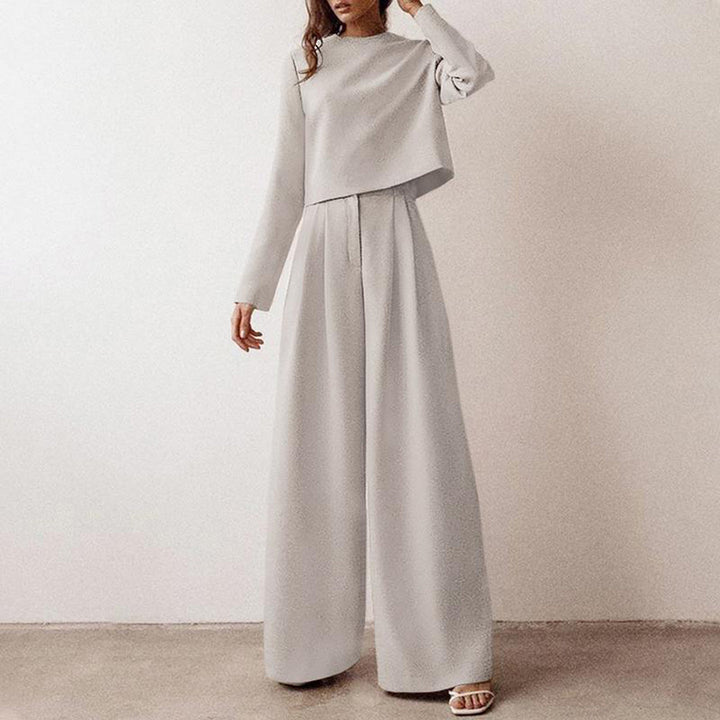Female model displaying a modern two-piece outfit with wide-leg trousers on a plain background.