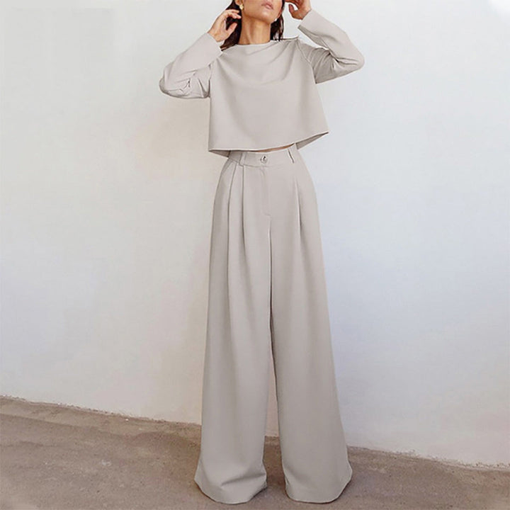 Woman wearing a matching long-sleeve top and high-waisted pants on a plain background.