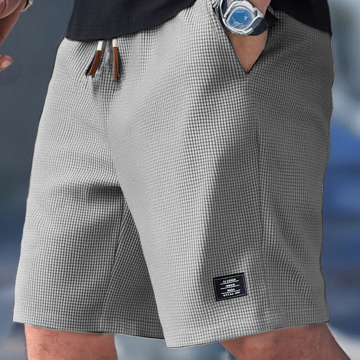Men turning slightly displaying side pockets shorts on plain background