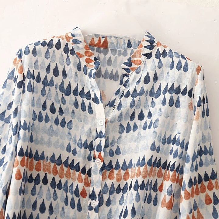 Chic button down blouse with playful abstract pattern shown on a model against a clean backdrop.