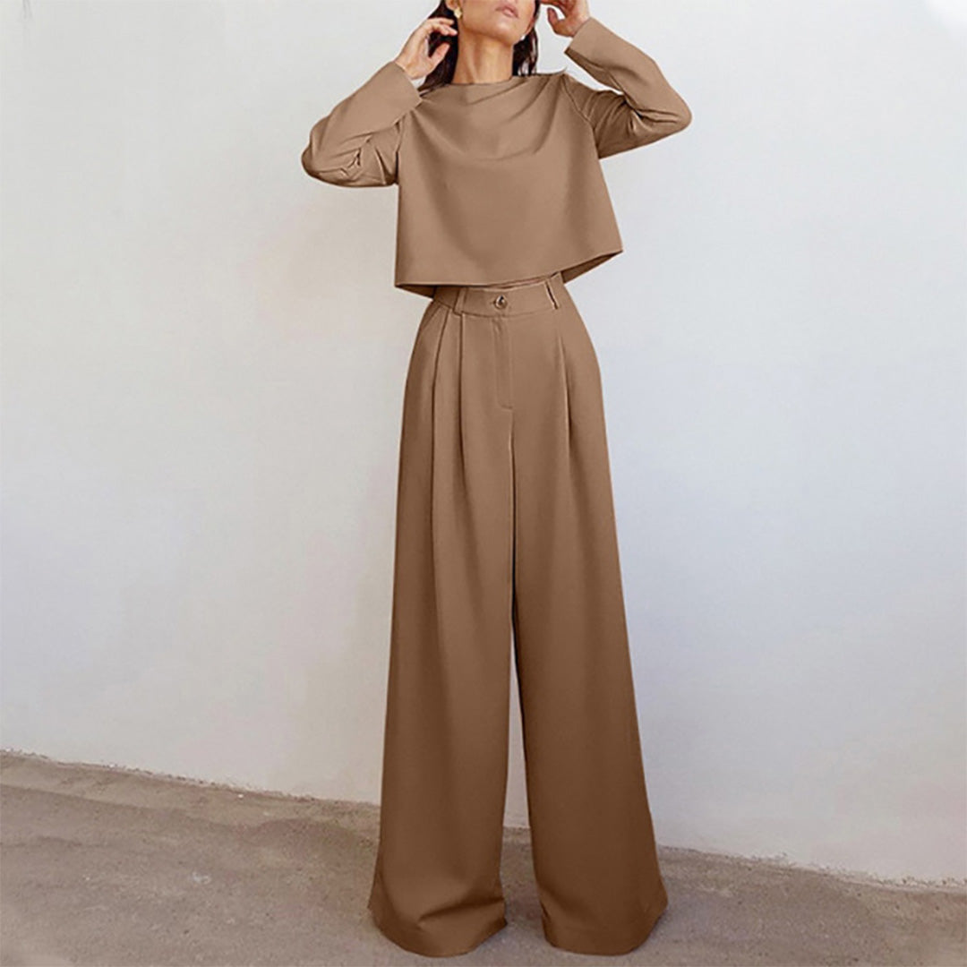 Woman wearing a fashion-forward two-piece ensemble with relaxed-fit pants on a plain background.