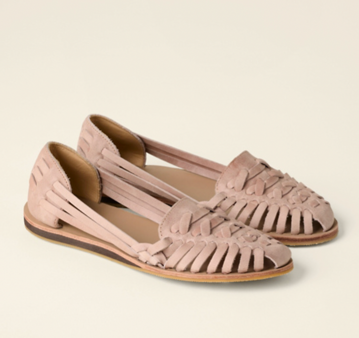 Woman showing side view of wedge sandals against a plain background.
