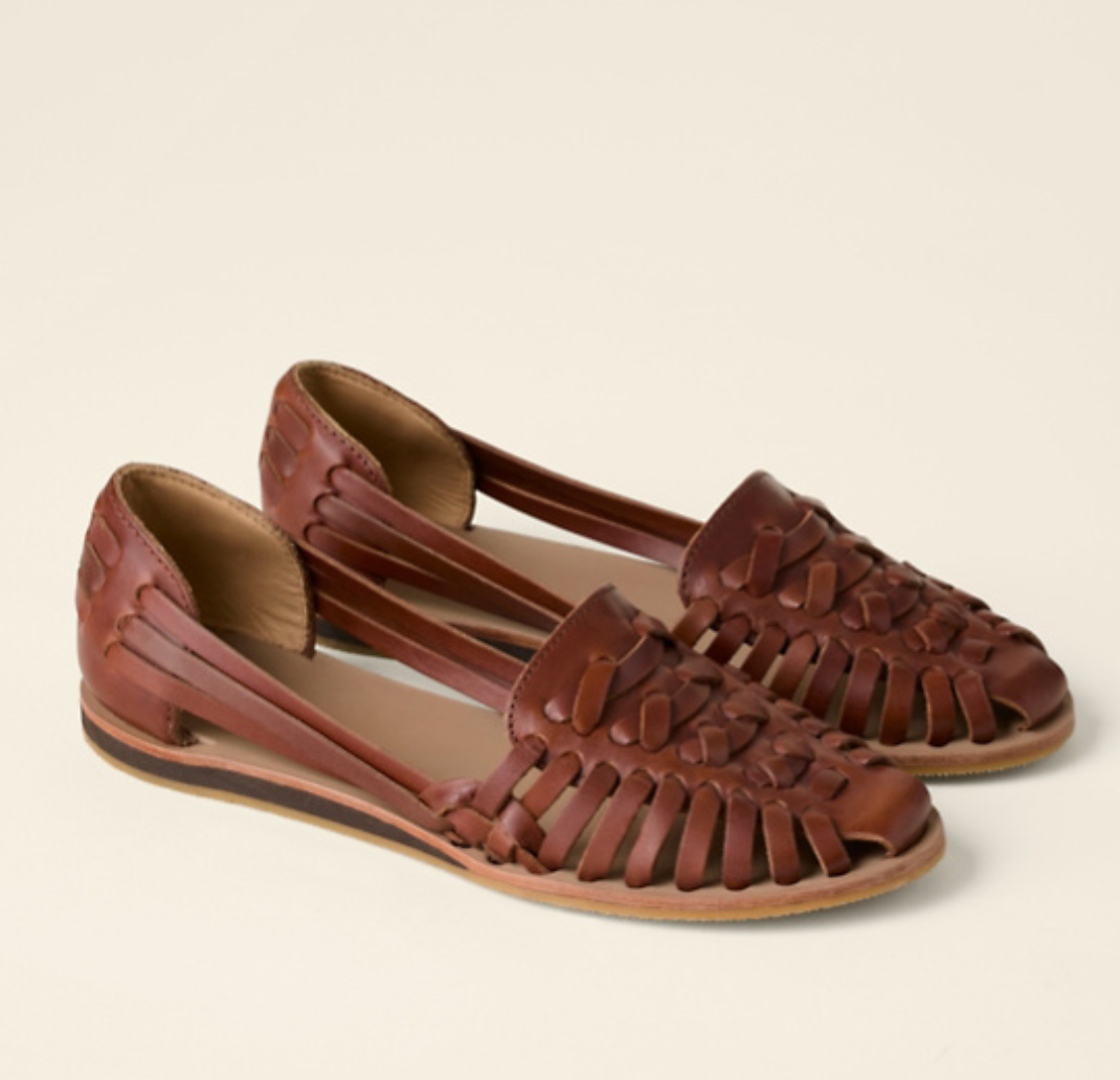 Female model wearing open-toe wedge sandals on a plain background.