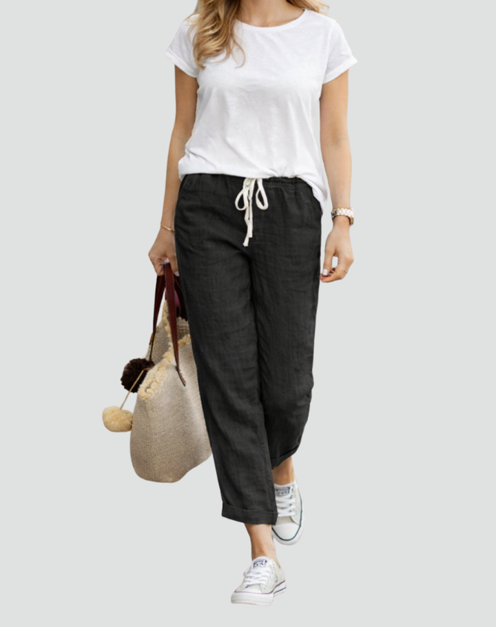  Female model displaying breathable linen trousers styled for warm-weather wear on a plain background.