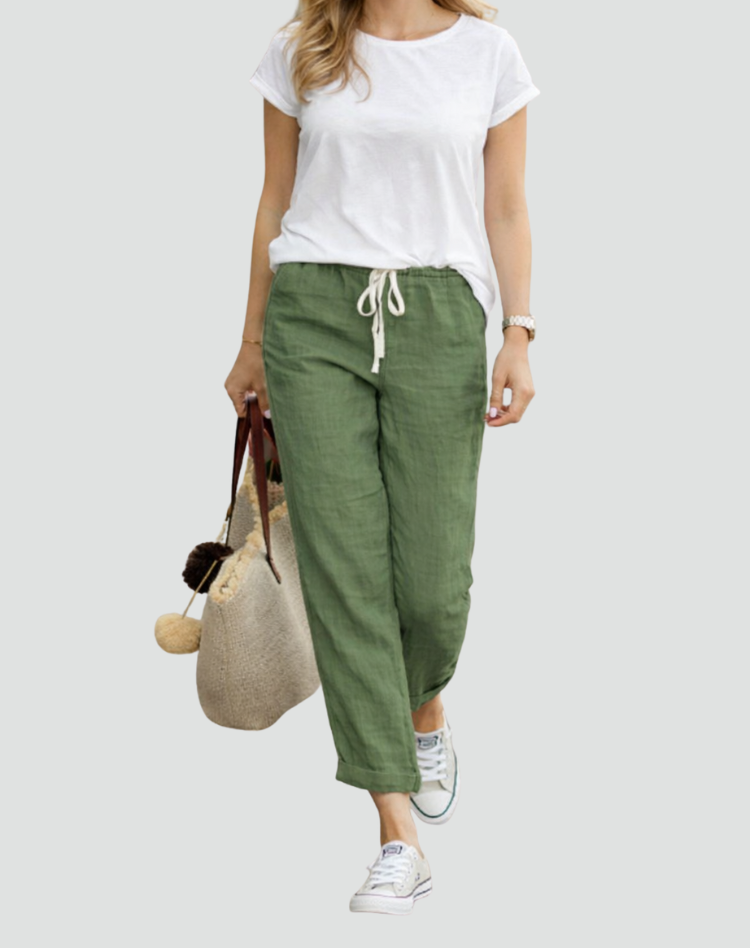  Woman showcasing lightweight linen trousers with a loose silhouette on a plain background.