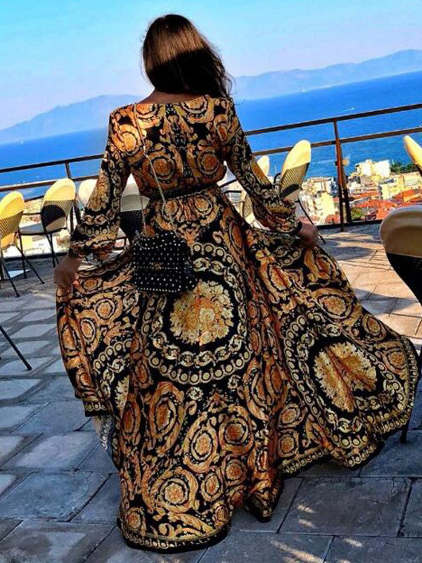 Woman posing in back angle, V-neck printed wrap maxi dress on a plain background.