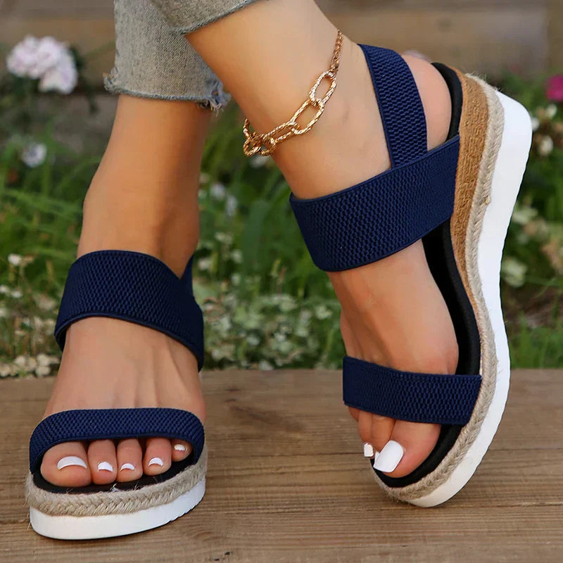 Foot model in casual summer sandals against brown floor.