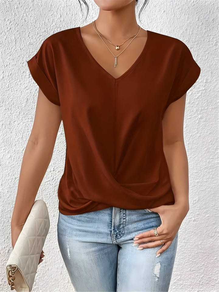 Soft blend women’s top featuring twist front detail with model on plain background.