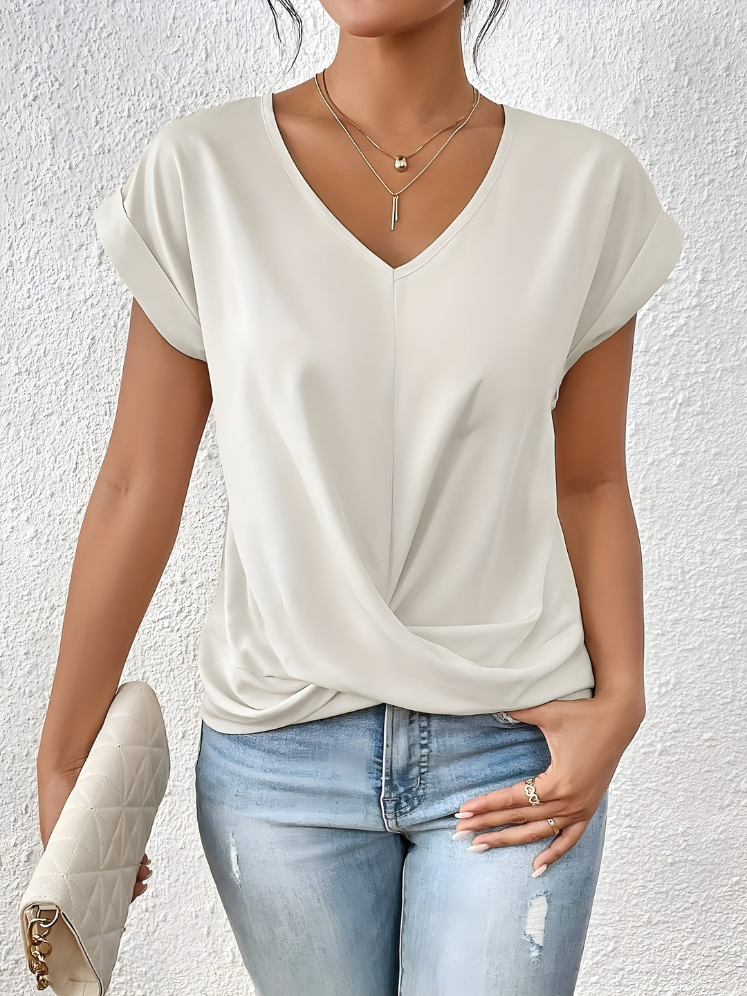 Casual dressy twist front women’s top with model on a plain background.