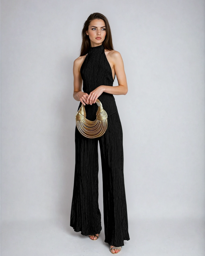 Model wearing a sleeveless pleated two-piece outfit with wide-leg trousers on a plain background.