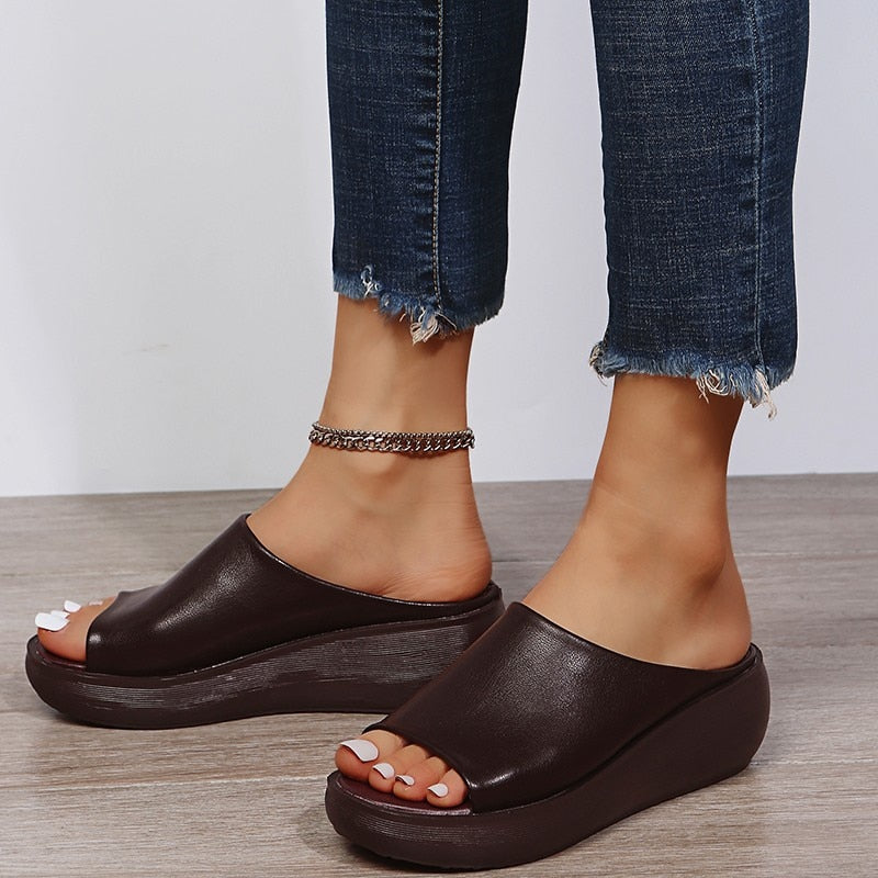 Close up straps on wedge sandals worn by woman plain background