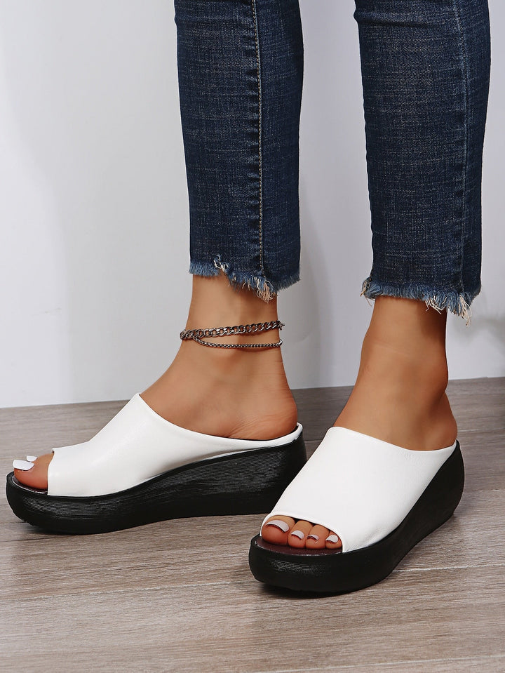 Angled front view of wedge sandals on woman plain background