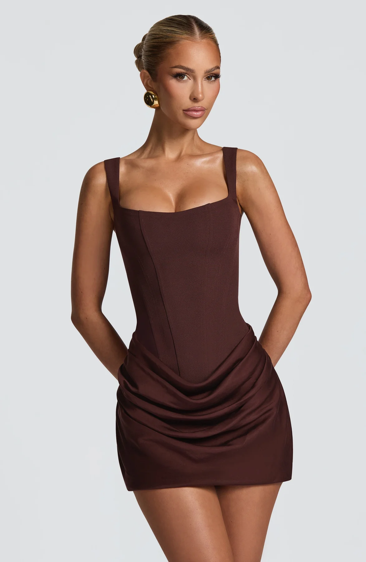 Female model wearing a draped mini dress with a square neckline on a plain background.