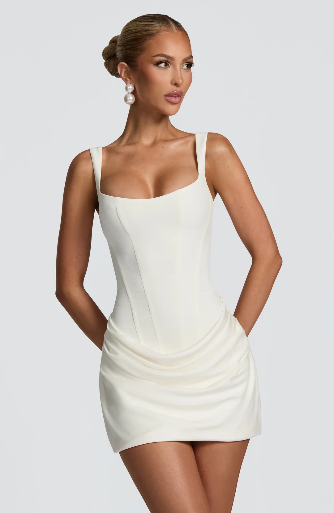 Female wearing a square neckline mini dress with wide straps against a plain background
