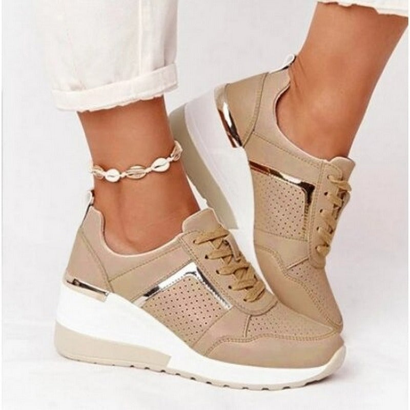 Beige wedge sneakers worn with white pants on a light background