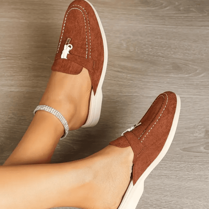 Top view foot highlighting tassel detail plain background neutral tone