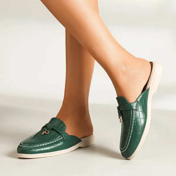 Stylish flat on foot from front, plain beige background.