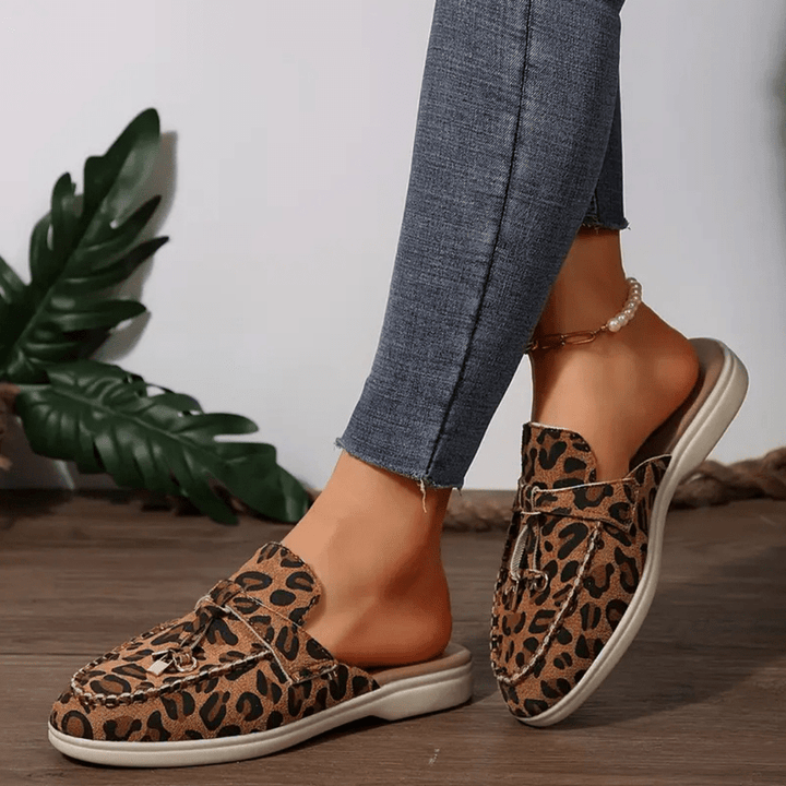 Close up foot wearing stylish loafers front angle plain background