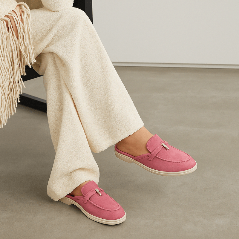 Woman model wearing slip-on mules front view on plain background.