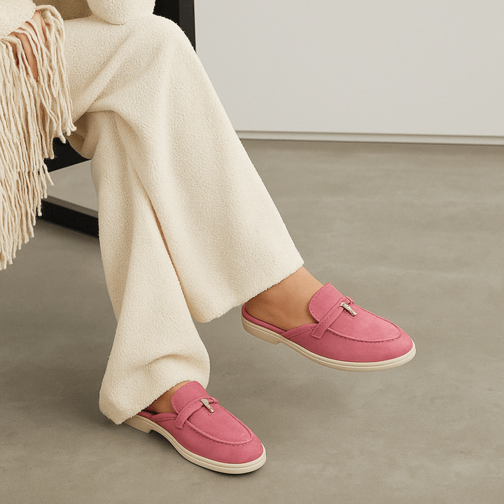 Woman model wearing slip-on mules front view on plain background.