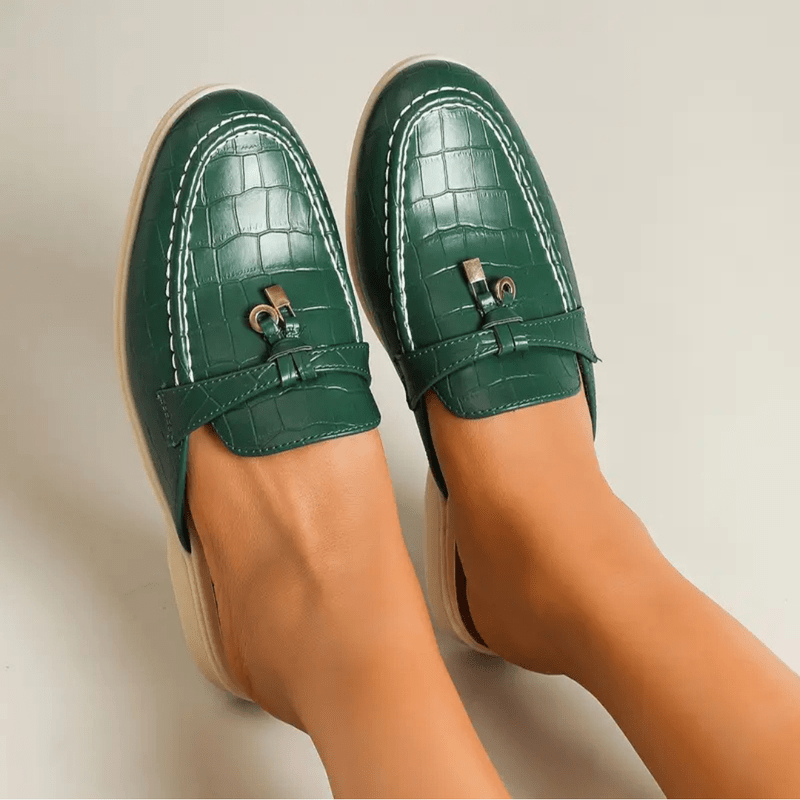 Model foot wearing trendy flat, plain beige background display.