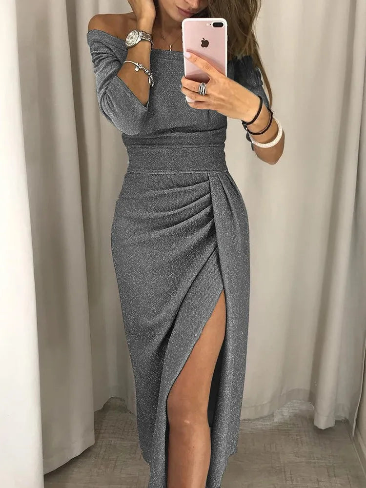  Woman wearing a shimmering off-shoulder dress with a front slit on a plain background.