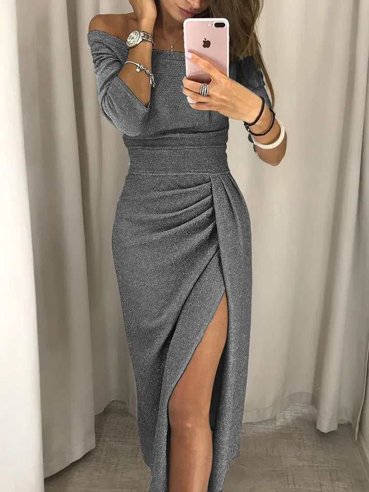  Woman wearing a shimmering off-shoulder dress with a front slit on a plain background.