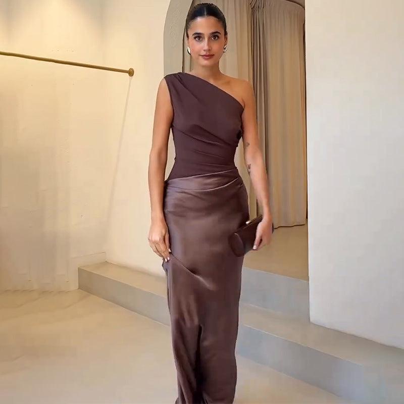 Woman in an elegant one-shoulder formal dress with a flowing silhouette on a plain background.