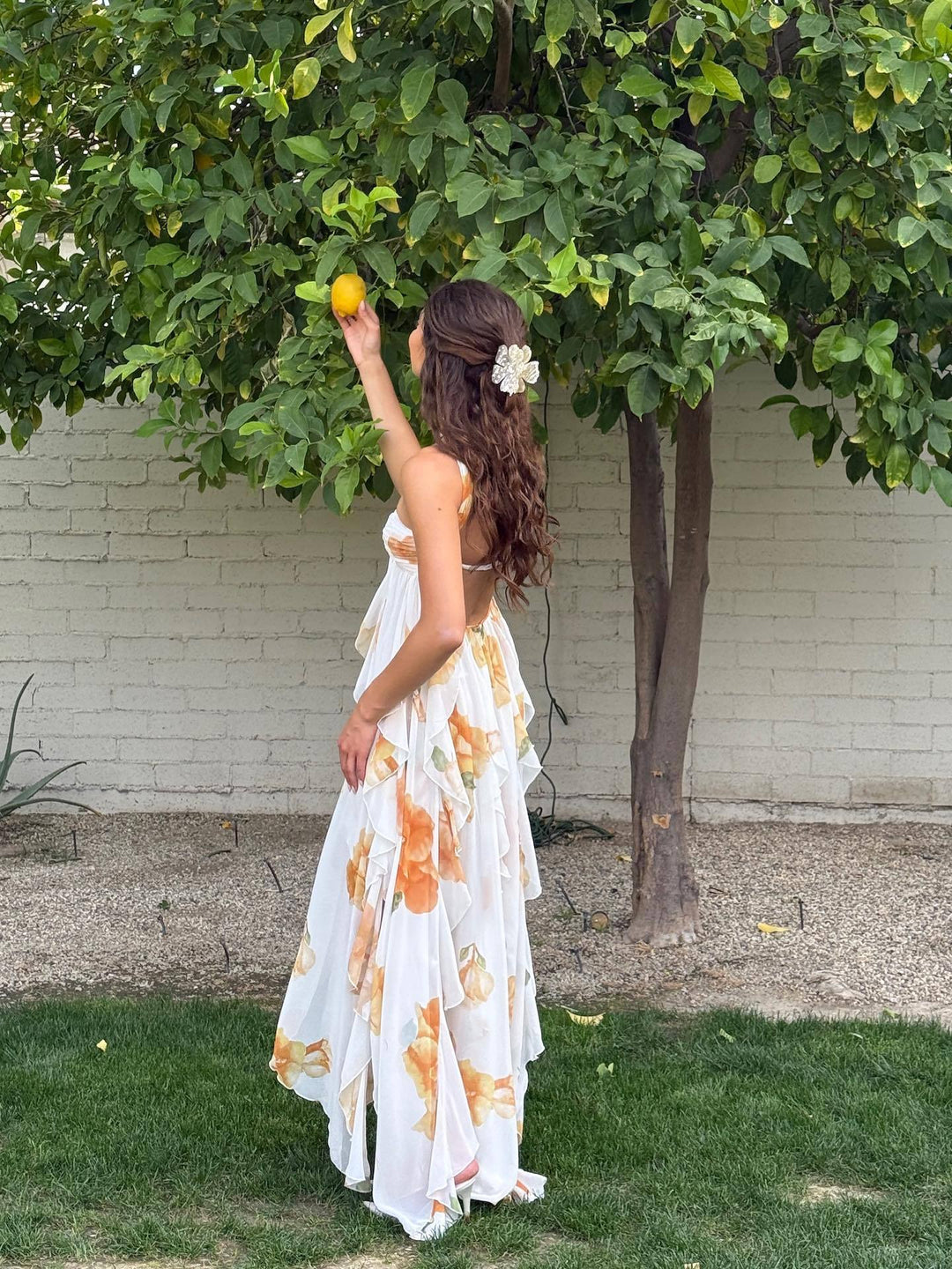 Female model posing in a sleeveless summer dress on a plain background.